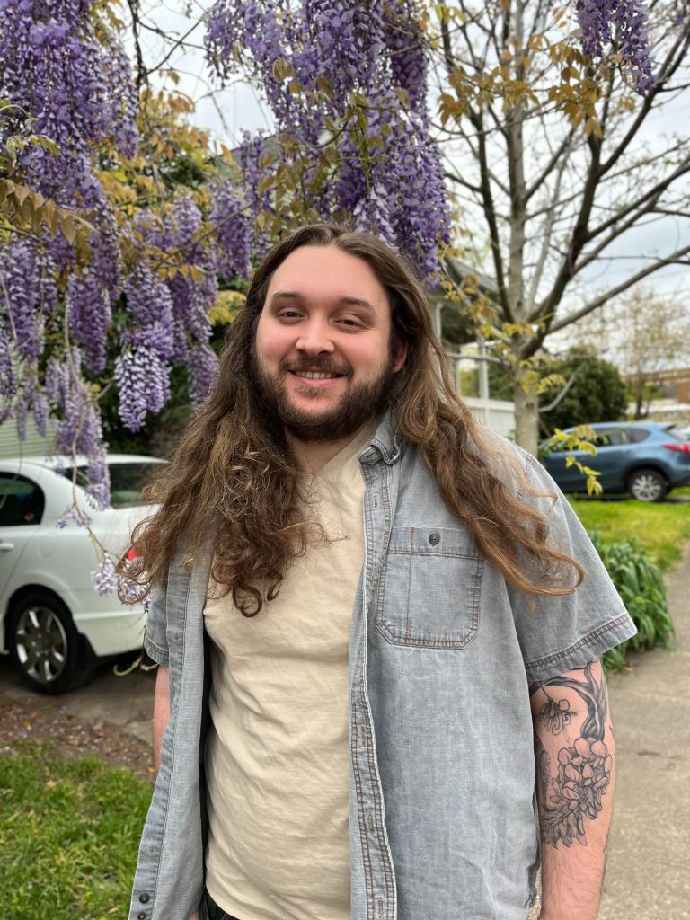Wil smiles at the camera from under a bough of wisteria